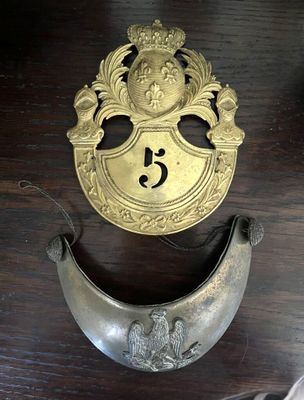 une plaque en laiton sur laquelle est représenté un visage, posée sur une table en bois