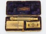 a gold colored box with a razor and a razor blade in it