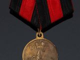 an old medal with a red and black ribbon hanging from it ' s neck