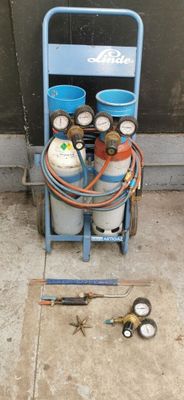 un chariot avec des bouteilles de gaz et un tuyau posé par terre