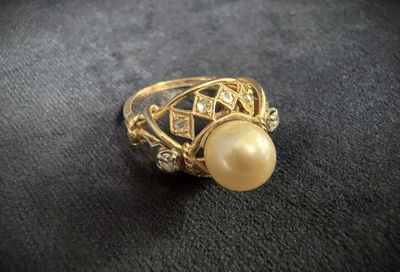 a close up of a gold ring with a pearl and diamonds