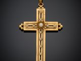 une croix en or avec une perle au centre, sur fond noir