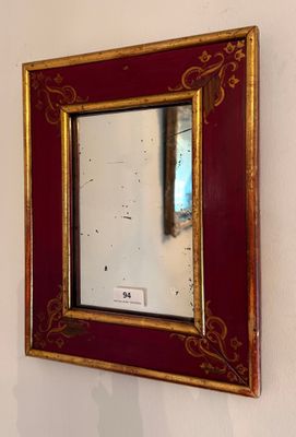 un miroir accroché au mur, avec un cadre rouge