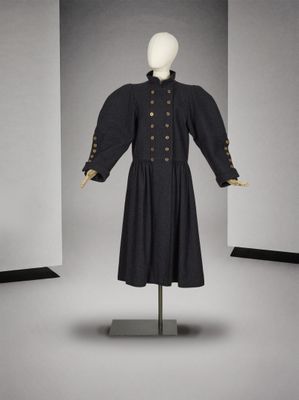 une photo d'une robe noire ornée de boutons dorés, présentée sur un mannequin