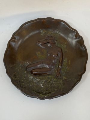 une sculpture en bronze représentant une femme assise sur un plateau