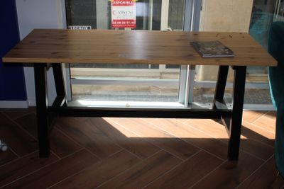 une table en bois sur laquelle est posé un livre, devant une fenêtre