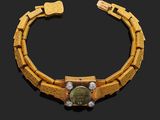 un bracelet en or orné d'une pierre verte et de diamants sur fond noir