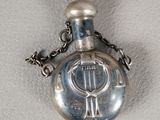 a silver pocket watch on a chain on a white surface