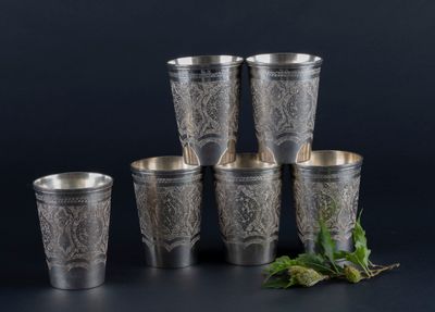 six silver cups with leaves on them and a sprig of mint