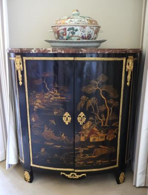 a black cabinet with a painting on it and a bowl on top of it