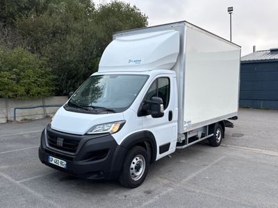 un camion blanc garé sur un parking, avec des arbres en arrière-plan