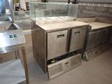 several stainless steel counter tops and a glass case in a kitchen