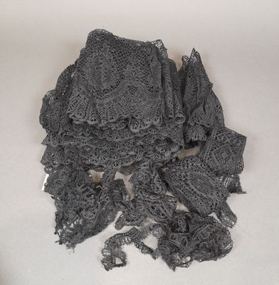 un tas de tissu noir au crochet posé sur une surface blanche