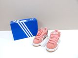 des baskets Adidas roses et blanches et une boîte bleue posée sur une table blanche
