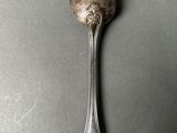 silver spoon on a gray surface with a small spoon sticking out of it ' s side