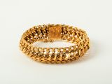 gros plan d'un bracelet en or sur une surface blanche