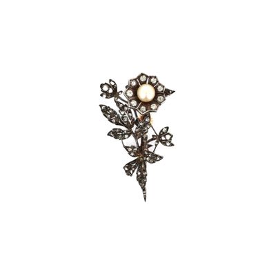 une photo d'une broche en forme de fleur, ornée de diamants et de perles