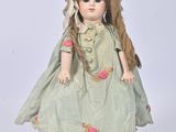 une poupée vêtue d'une robe verte et d'un chapeau