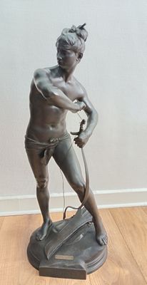 une statue représentant un homme tenant une batte de baseball, posée sur un plancher en bois