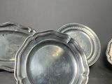 three silver plates on a table with a black background