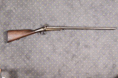 un fusil posé par terre à côté d'une bouteille de bière