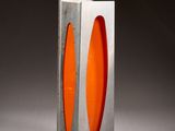 orange glass in a silver metal box on a white surface