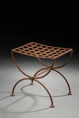 un petit tabouret en métal orné d'un motif en treillis