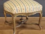 un petit tabouret avec une assise rayée, posé sur un plancher en bois