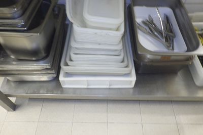 Plusieurs plateaux de nourriture sont empilés sur une étagère métallique dans une cuisine