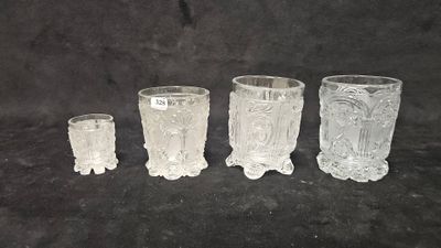 four clear glass vases sitting next to each other on a black surface
