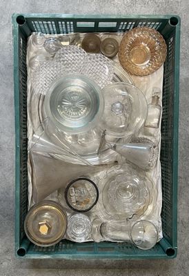 un panier vert rempli d'objets en verre posé par terre
