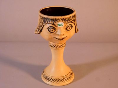 un petit vase orné d'un visage, posé sur une table