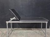 un banc noir sur lequel est posé un ordinateur portable, devant un mur noir