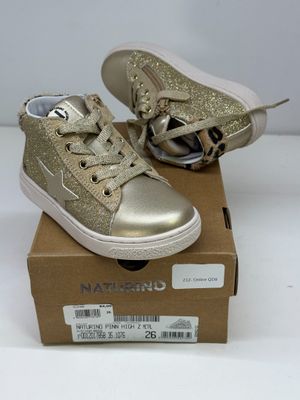 des baskets à paillettes dorées pour filles, dans une boîte posée sur une surface blanche