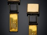 two gold and black earrings with square shapes on a black background