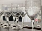 several empty wine glasses lined up on a shelf in front of a mirror