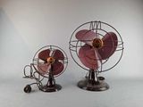 two small metal fans sitting side by side on a white surface