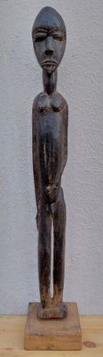 une petite statue représentant un homme debout sur un socle en bois