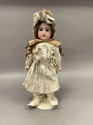 poupée en porcelaine représentant une jeune fille vêtue d'une robe blanche et d'un bonnet