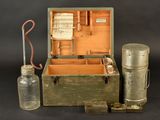 an old box with a glass bottle and a bottle of water