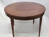 une table ronde en acajou avec des pieds en laiton et un plateau en bois
