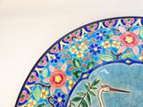 une assiette colorée ornée d'un oiseau, posée sur une table