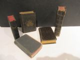 Plusieurs vieux livres sont posés les uns à côté des autres sur une surface blanche.