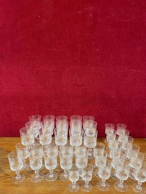 de nombreux verres posés sur une table, avec un mur rouge en arrière-plan