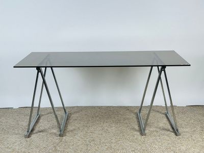 une photo d'une table en verre avec des pieds en métal posée sur un sol recouvert de moquette