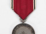 an old medal with a red ribbon on a white background