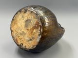 un vase brun posé sur une surface blanche