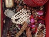 une boîte rouge remplie de bijoux variés, posée sur un plan de travail en marbre