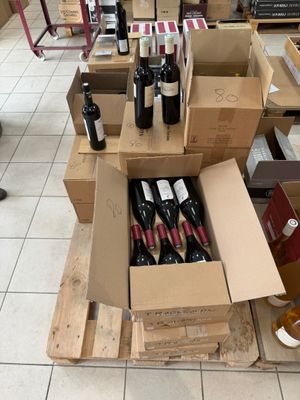 Des cartons de vin sont empilés sur des palettes dans un magasin