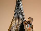 statue of a native american indian standing next to a teepee